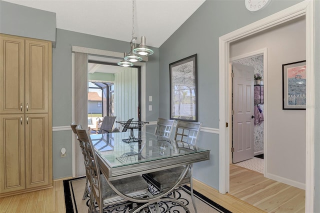 dining room with lofted ceiling and light hardwood / wood-style floors