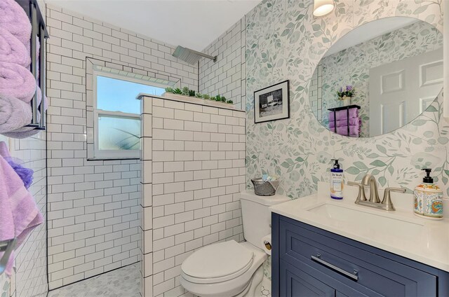 bathroom with vanity, tiled shower, and toilet