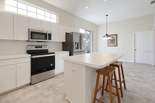 kitchen featuring tasteful backsplash, white cabinetry, hanging light fixtures, a center island, and stainless steel appliances