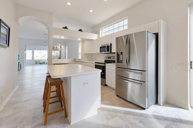 kitchen with a breakfast bar, sink, appliances with stainless steel finishes, a kitchen island, and white cabinets