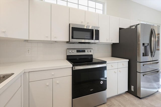 kitchen featuring decorative backsplash, white cabinets, and appliances with stainless steel finishes