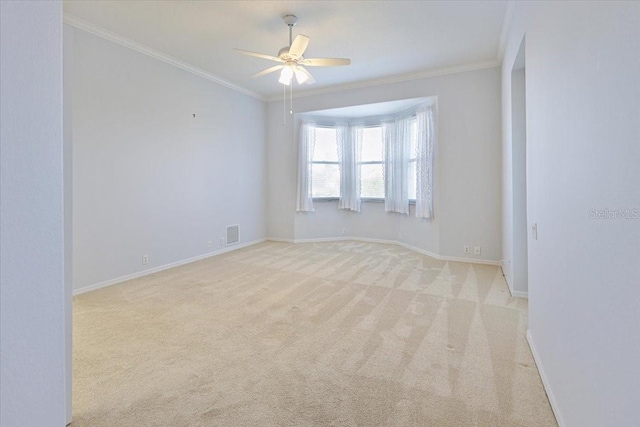 carpeted spare room featuring crown molding and ceiling fan