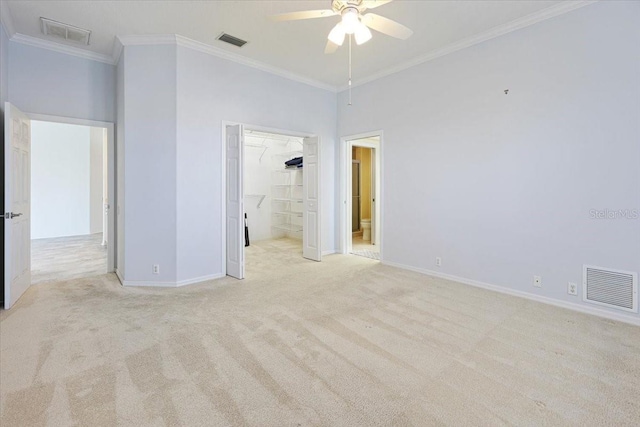 unfurnished bedroom featuring crown molding, connected bathroom, a walk in closet, light colored carpet, and a closet