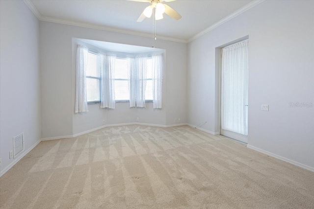 spare room featuring crown molding, light colored carpet, and ceiling fan