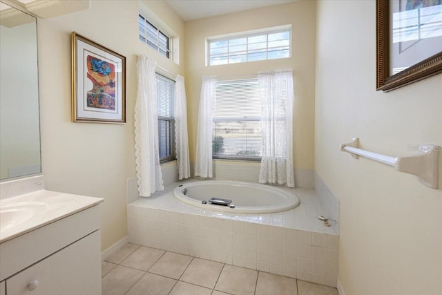 bathroom featuring a relaxing tiled tub, a healthy amount of sunlight, vanity, and tile patterned flooring