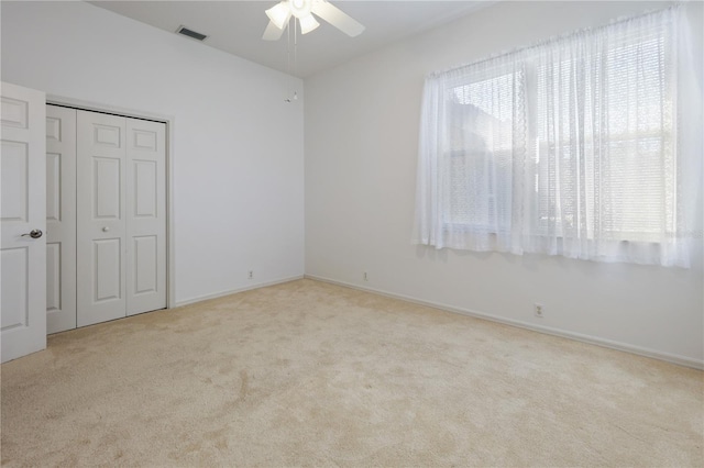 unfurnished bedroom with light carpet, ceiling fan, and a closet