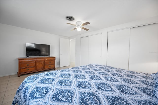 tiled bedroom featuring two closets and ceiling fan