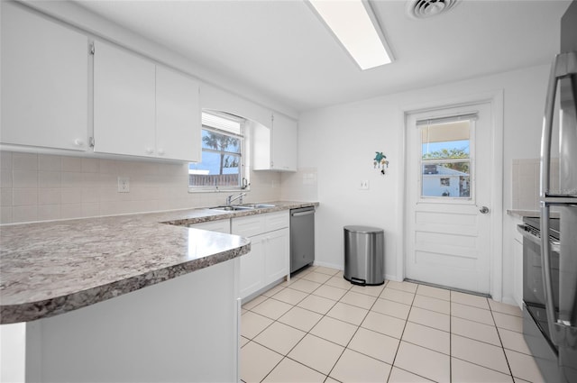 kitchen featuring light tile patterned floors, dishwasher, white cabinetry, fridge, and tasteful backsplash