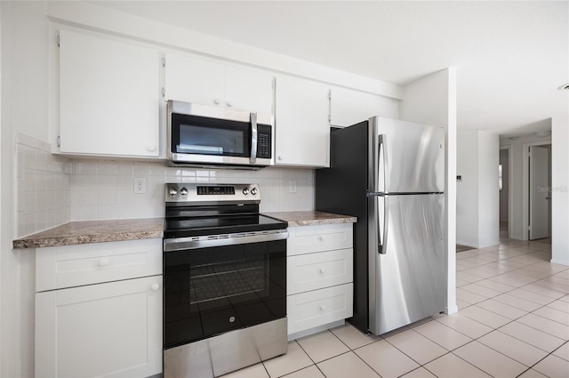 kitchen featuring tasteful backsplash, appliances with stainless steel finishes, light tile patterned floors, and white cabinets