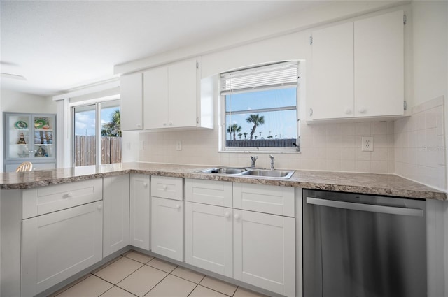 kitchen with sink, white cabinetry, light tile patterned floors, dishwasher, and backsplash