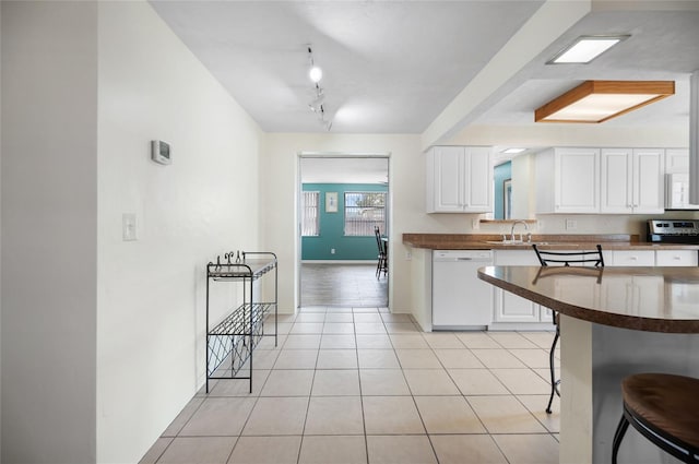 kitchen with light tile patterned floors, white appliances, a breakfast bar, track lighting, and white cabinets