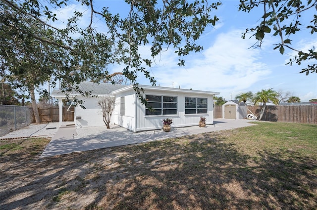 rear view of property with a storage shed, a patio area, and a lawn