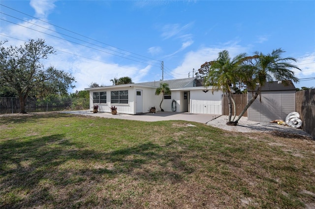 back of house with a storage unit, a lawn, and a patio area