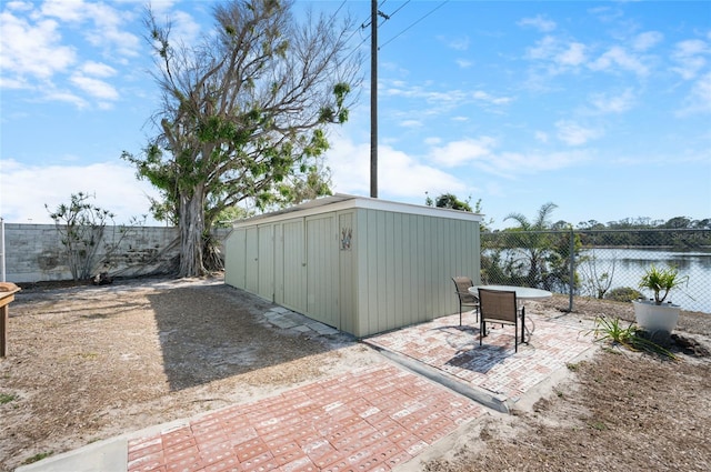 view of patio with a water view and a storage shed