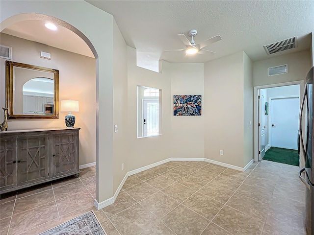 corridor featuring light tile patterned flooring and a textured ceiling