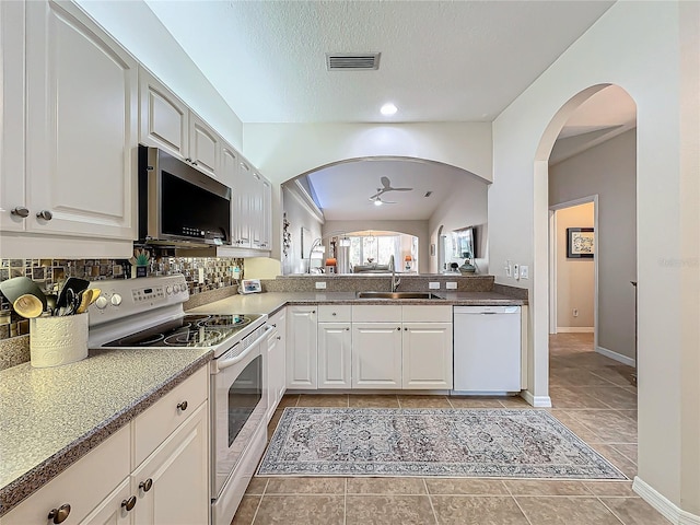 kitchen featuring sink, white appliances, light tile patterned floors, a textured ceiling, and white cabinets