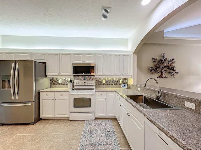 kitchen featuring tasteful backsplash, sink, white cabinets, light tile patterned floors, and stainless steel appliances