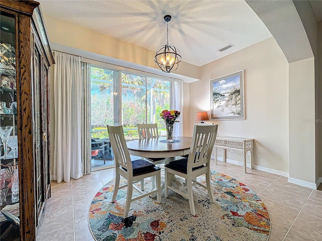 dining room with light tile patterned floors, a textured ceiling, and an inviting chandelier