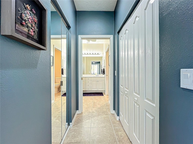 corridor featuring a textured ceiling and light tile patterned flooring