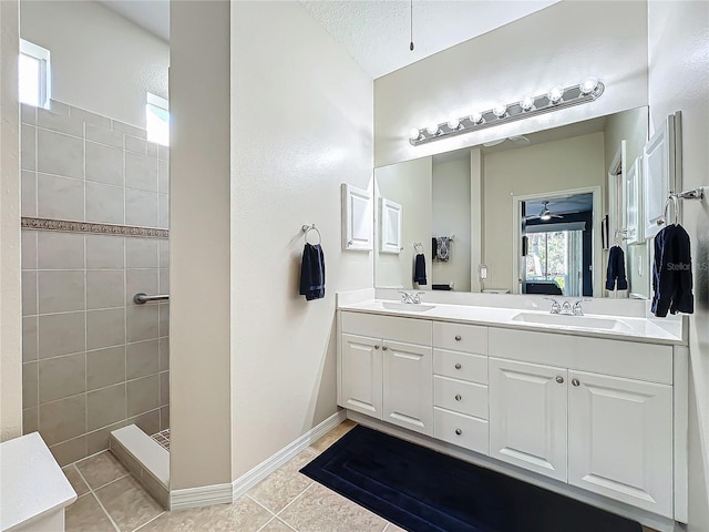 bathroom with ceiling fan, vanity, tile patterned flooring, and a tile shower