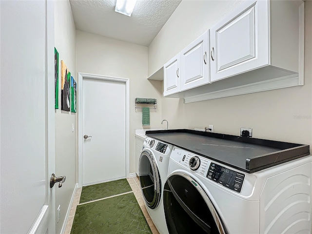 clothes washing area with a textured ceiling, cabinets, and washing machine and clothes dryer