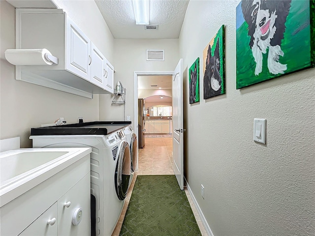 laundry area with sink, washing machine and dryer, cabinets, and a textured ceiling