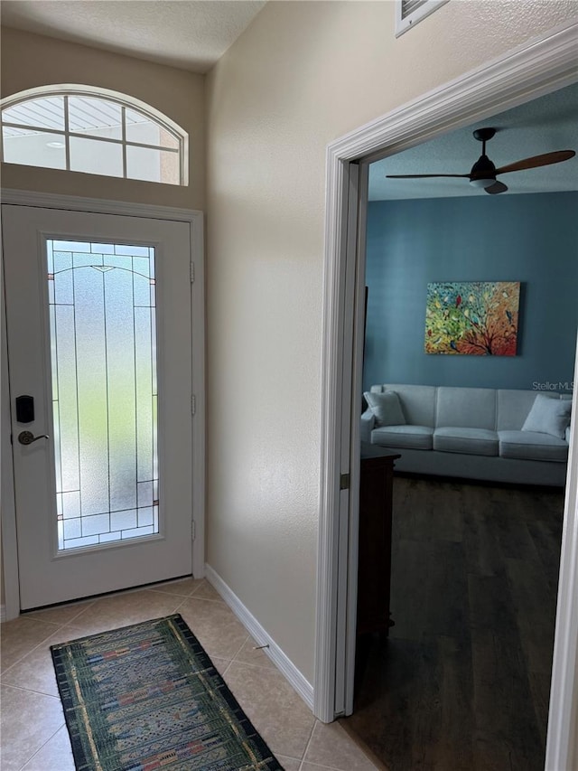 entryway featuring ceiling fan, a textured ceiling, and light tile patterned floors