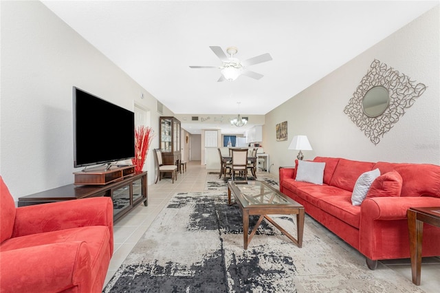 living room featuring ceiling fan with notable chandelier and light tile patterned floors