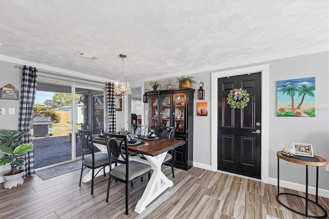 dining space featuring a notable chandelier, hardwood / wood-style flooring, ornamental molding, and a textured ceiling