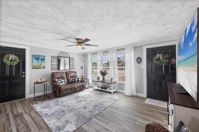 living room featuring ceiling fan, a textured ceiling, and light hardwood / wood-style flooring