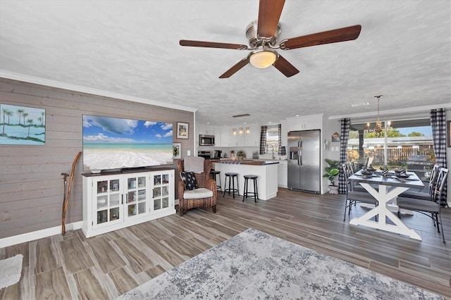 living room featuring ornamental molding, wooden walls, sink, and a textured ceiling