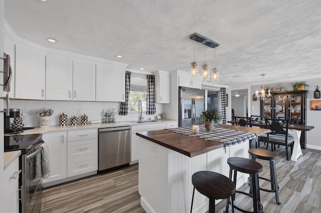 kitchen featuring sink, decorative light fixtures, a center island, appliances with stainless steel finishes, and white cabinets