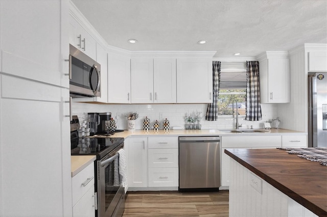 kitchen with butcher block countertops, sink, appliances with stainless steel finishes, decorative backsplash, and white cabinets