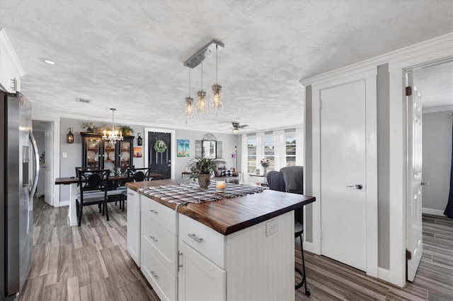 kitchen with a kitchen island, decorative light fixtures, butcher block counters, white cabinets, and stainless steel refrigerator with ice dispenser