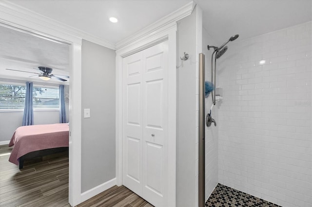 interior space featuring hardwood / wood-style flooring, ornamental molding, a tile shower, and ceiling fan