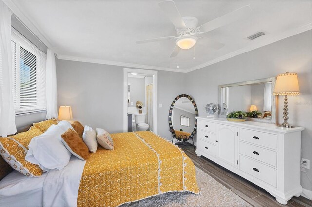 bedroom featuring ornamental molding, dark wood-type flooring, ensuite bathroom, and ceiling fan