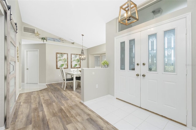 foyer with vaulted ceiling, a notable chandelier, light hardwood / wood-style floors, and french doors