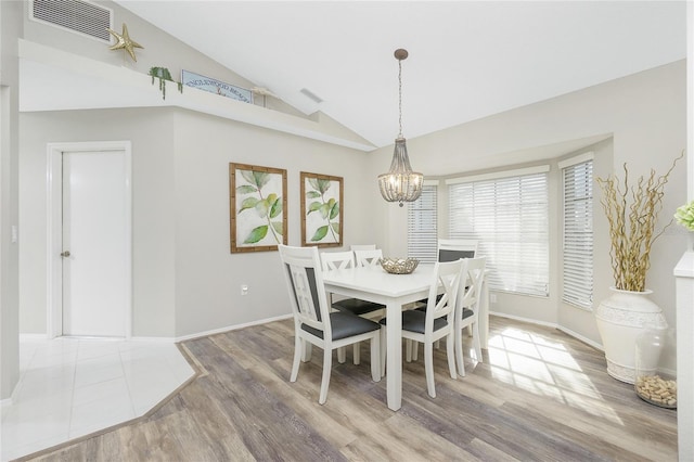 dining room with an inviting chandelier, wood-type flooring, and vaulted ceiling