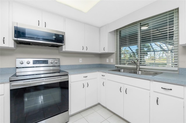 kitchen with sink, light tile patterned floors, white cabinets, and appliances with stainless steel finishes