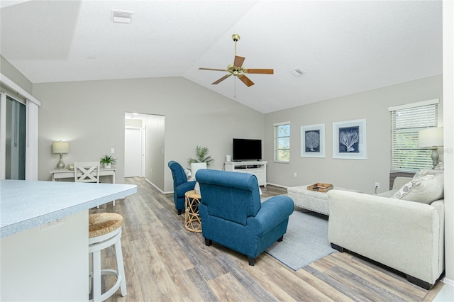 living room featuring ceiling fan, wood-type flooring, and vaulted ceiling