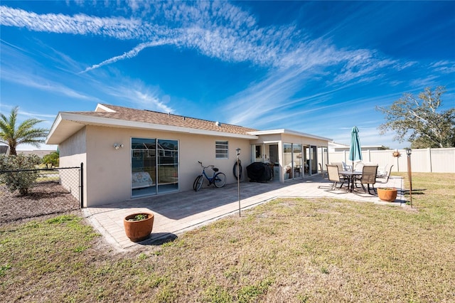 back of house with a yard, a patio area, fence, and stucco siding