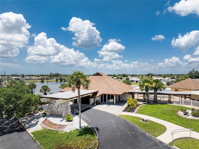 view of property's community with a yard, a water view, and driveway