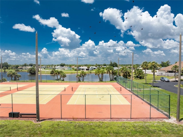 view of sport court featuring a water view and fence