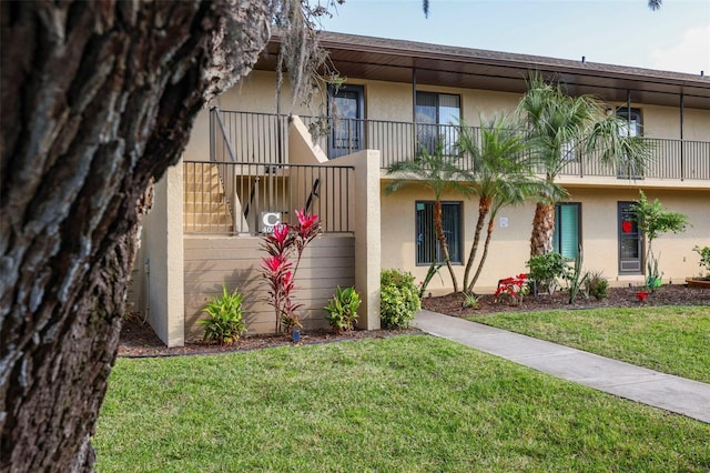 view of property featuring a balcony and a front yard