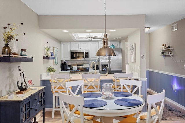 dining area featuring ceiling fan, a raised ceiling, and sink