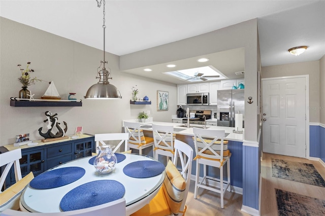 dining area with ceiling fan, light hardwood / wood-style floors, and sink