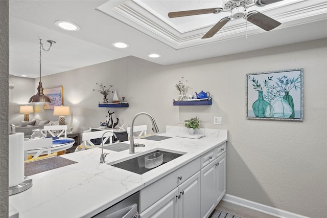 kitchen featuring sink, light stone counters, hanging light fixtures, ceiling fan, and white cabinets