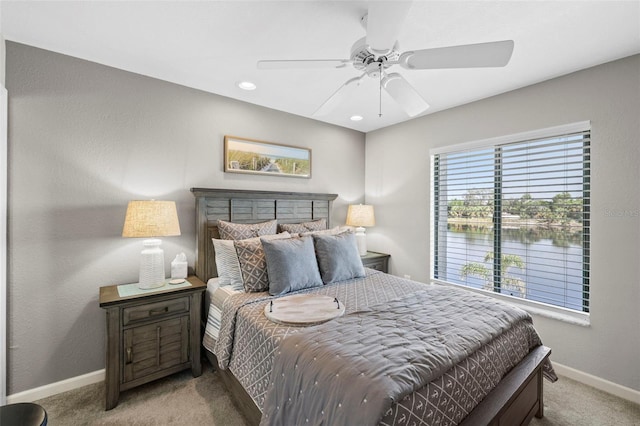 bedroom featuring light colored carpet, ceiling fan, and a water view