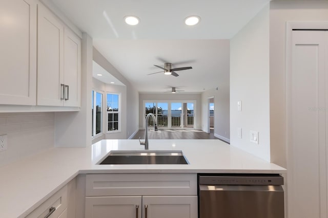 kitchen featuring dishwasher, open floor plan, light countertops, white cabinetry, and a sink