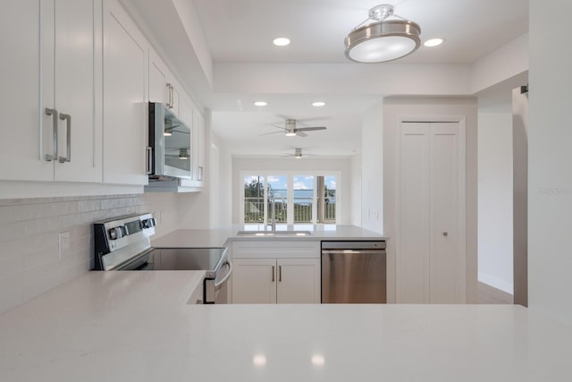 kitchen with stainless steel appliances, light countertops, decorative backsplash, white cabinets, and a sink